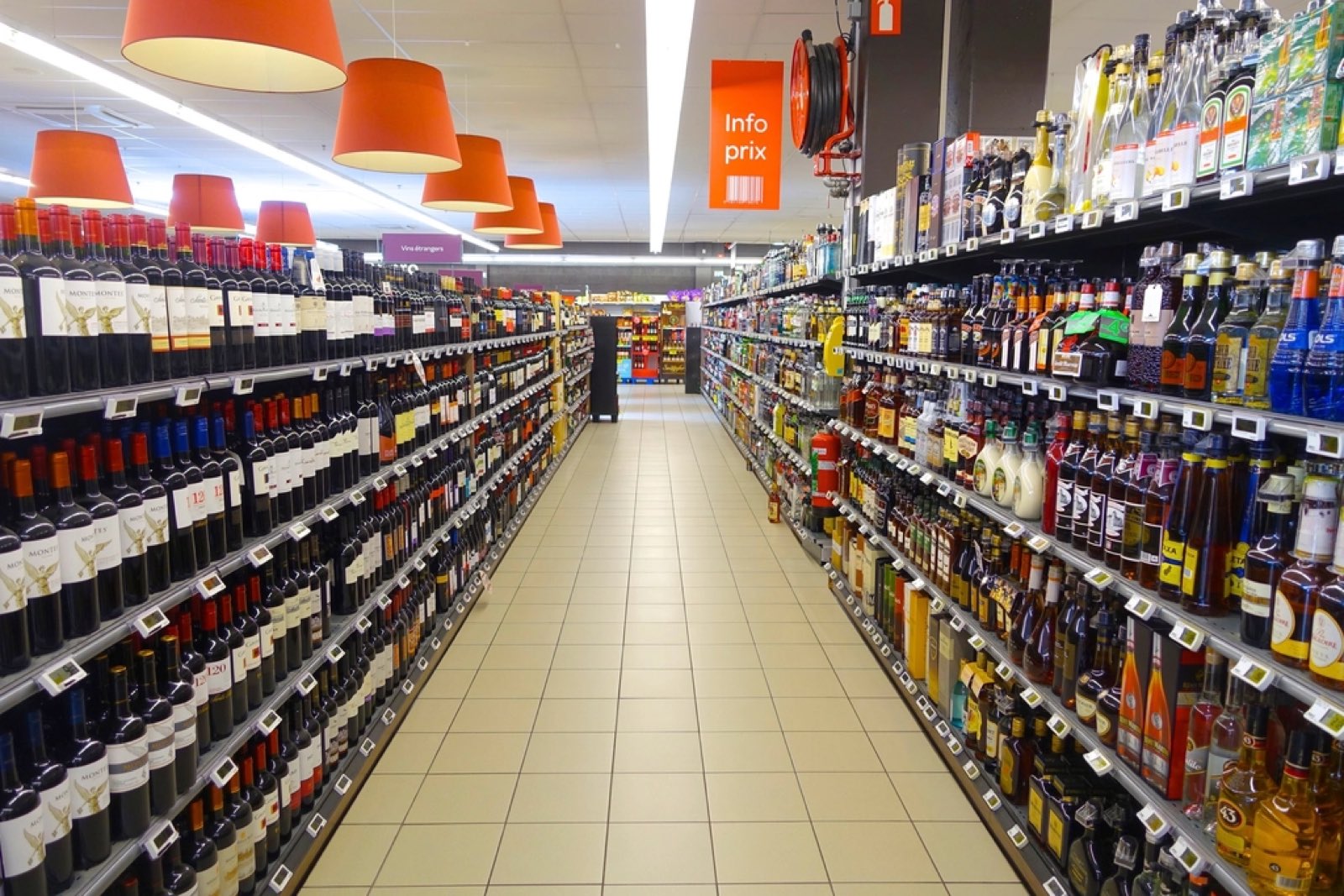 A long, brightly lit supermarket aisle lined with shelves